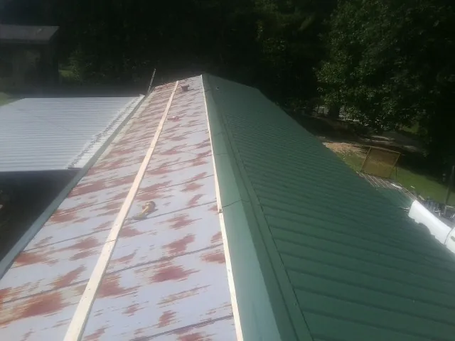 Old rusted panels beside newly installed green metal roofing — Wind Damage Roof Repair by Roofing Brothers in Indian Head