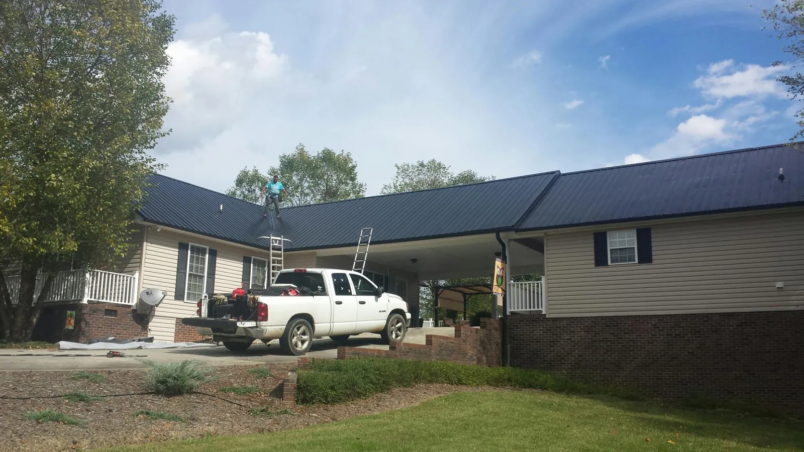 Black metal roof over a home and attached breezeway with ladders set in Indian Head