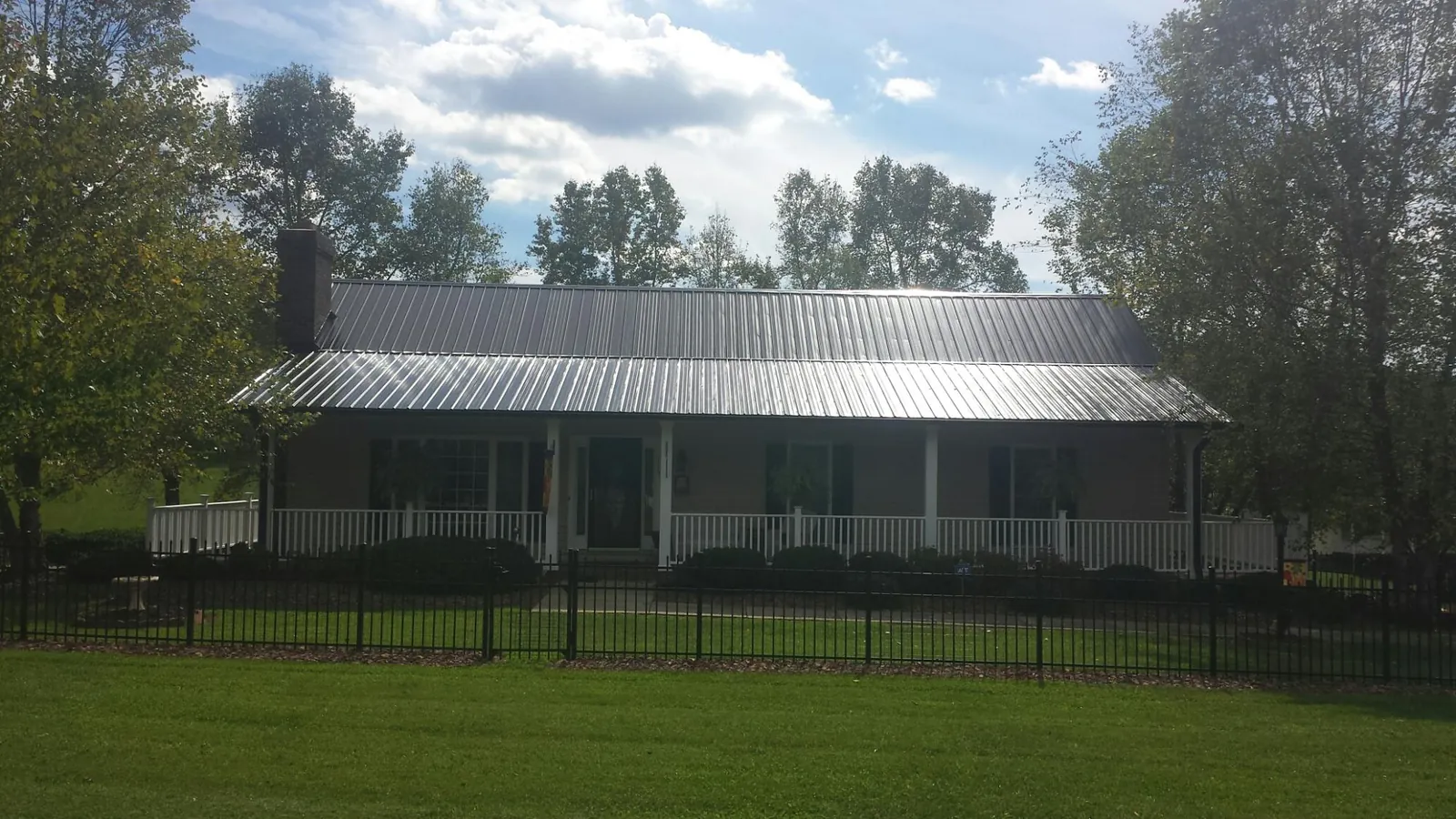 Gray metal roof on a brick ranch with a full width front porch — Gutter Guard Installation work by our crew in Indian Head